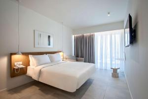 sypialnia z dużym białym łóżkiem i oknem w obiekcie Radisson Resort Plaza Skiathos w mieście Kanapitsa