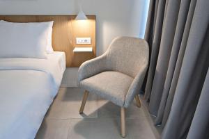 1 dormitorio con silla junto a la cama en Radisson Resort Plaza Skiathos en Kanapitsa