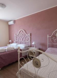 1 dormitorio con 2 camas y pared de color rosa en Agriturismo I Grappoli, en Alberese