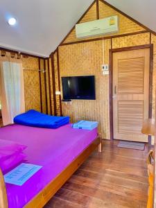 a bedroom with a large purple bed with a flat screen tv at Seamthong Resort เสียมทองรีสอร์ท in Ban Siam
