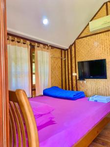 a bedroom with a large pink bed with a tv at Seamthong Resort เสียมทองรีสอร์ท in Ban Siam