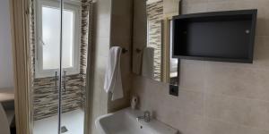 a bathroom with a tub and a tv on the wall at Pensión A Carballeira in Villalba