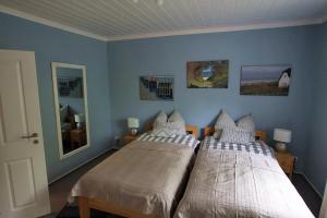 two beds in a bedroom with blue walls at Ferienwohnung an Schleusenanlage NOK in Brunsbüttel