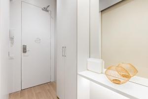 W białej łazience znajduje się lustro i kuchenka mikrofalowa. w obiekcie Canela Homes BARCELONA MARINA w Barcelonie +37 zdjęć