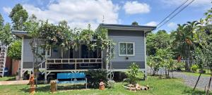 a gray house with a porch in the yard at Tarmtawan garden home in Nakhon Nayok