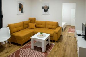 a living room with a yellow couch and a table at Apartmani Pijemont in Višegrad