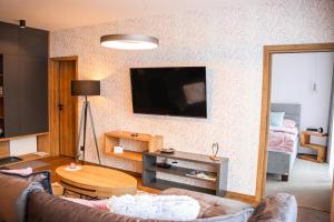 a living room with a couch and a television on a wall at Apartman NISA - Ovruč in Štrbské Pleso