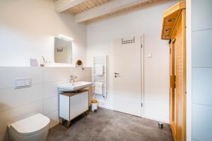 uma casa de banho branca com um WC e um lavatório em NordseeResort Büsum Ferienhaus 63 Küstenlodge em Büsum