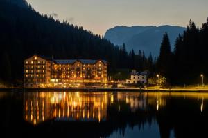 a large building sitting next to a lake at night at Grand Hotel Misurina in Misurina