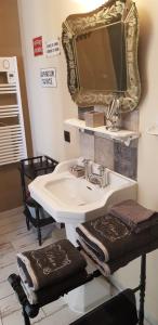 a bathroom with a sink with a mirror and towels at La Maison de Manon 