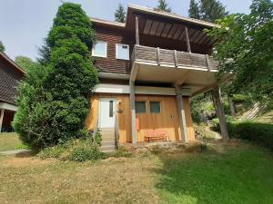 ein kleines Haus mit einer Veranda und einem Baum in der Unterkunft Ferienhaus Bad Hundertpfund Typ A in Großbreitenbach