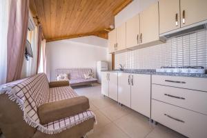 a kitchen with white cabinets and a couch in it at Karia Apart&Pension in Mesudiye