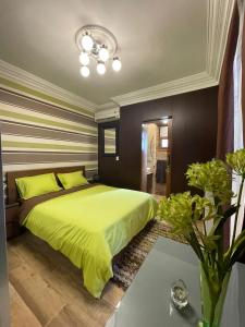 Luxury Mamoura Alexandria Apartment في الإسكندرية: غرفة نوم بسرير اخضر كبير مع مخدات صفراء