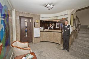 Een man in een smoking die voor een bar staat. bij Kucuk Velic Hotel in Gaziantep