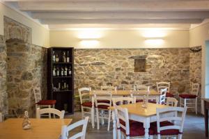 um restaurante com mesas e cadeiras de madeira e uma parede de pedra em Agriturismo I Giunchi em Mochignano