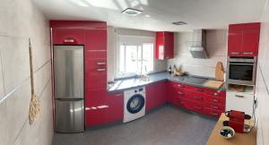 a kitchen with red cabinets and a washer and dryer at Casa Tajo in Tarifa