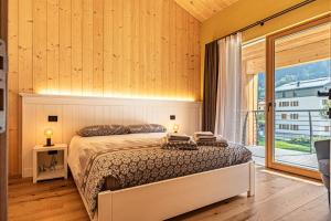 a bedroom with a bed and a large window at Ciasa Fatati in Pinzolo