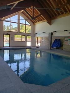 a large swimming pool with blue water in a building at Apt 2 chambres en duplex Chalet des Rennes Vars 2000m Piscine intérieure et extérieure in Vars