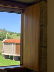 a window in a room with a view of a house at Albergue Rectoral San Mamede da Pena EXCLUSIVE FOR PILGRIMS in Negreira