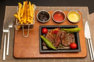 a cutting board with a steak and french fries at Euro Park Hotel Bursa in Bursa