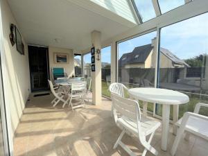 a patio with white chairs and tables and windows at Maison familiale à Fouesnant avec jardin clos, proche plages et centre-ville - FR-1-481-103 in Fouesnant