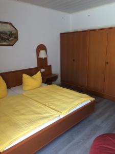 a bedroom with a bed with yellow sheets and wooden cabinets at Ferienwohnung auf dem Land Wiesenblick Sonnenberg Grambow in Grambow