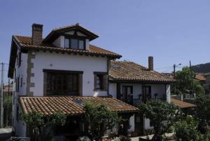 een wit huis met een betegeld dak bij Casa Mari Paz Trasvía in Comillas