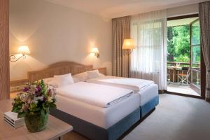 um quarto de hotel com uma cama e uma varanda em Dorint Sporthotel Garmisch-Partenkirchen em Garmisch-Partenkirchen
