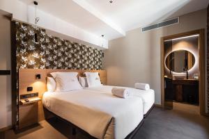 a bedroom with a large white bed and a mirror at Hotel Atari in Donostia-San Sebastián