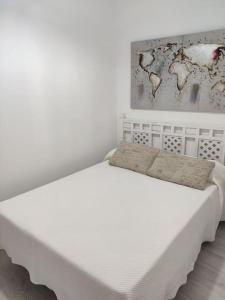 a white bed in a room with a painting on the wall at Ave Maria 8 in Tarifa