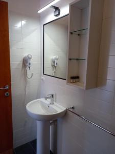 La salle de bains blanche est pourvue d'un lavabo et d'un miroir. dans l'établissement Il Roseto, à Procchio