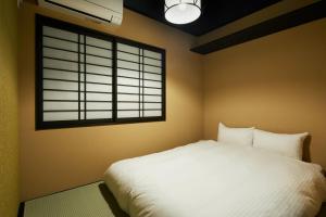 ein Schlafzimmer mit einem weißen Bett und einem Fenster in der Unterkunft TSUBOMI luxury Inn Shimabara Bettei 2 in Kyoto