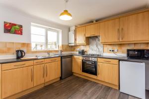 a large kitchen with wooden cabinets and a window at Luke Stays - Windmill Way in Gateshead