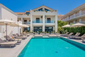 a swimming pool with chairs and umbrellas next to a building at Dannas Boutique Hotel & Suites in Tsilivi