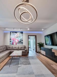 a living room with a couch and a tv and a chandelier at Apartament VIP CENTRUM in Mrągowo