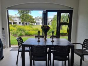 a dining room table with chairs and a large window at Keurbooms River Apartment in Plettenberg Bay