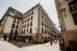 a group of people walking on a street with buildings at Hotel Atari in San Sebastián