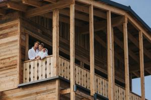 a couple standing on a balcony of a wooden house at Ortner's Resort in Bad Füssing