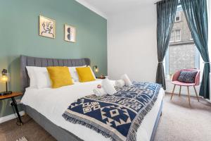 ein Schlafzimmer mit einem großen Bett und einem rosa Stuhl in der Unterkunft Cozy with Character Lovely Central Apartment in Edinburgh