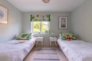 two beds in a room with a table and a window at The Cottage in the Clouds in Marlborough