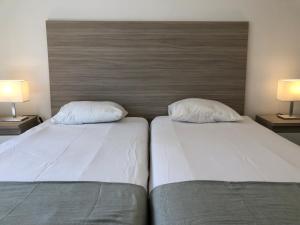 2 letti con lenzuola e cuscini bianchi in una camera da letto di Be Lisbon Residence Marquês a Lisbona