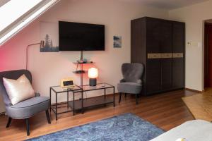 a living room with two chairs and a tv at Szent Imre Apartman in Veszprém