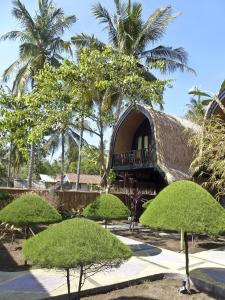 una casa con techo de paja con árboles y arbustos en Villas Ganjor en Gili Meno
