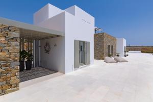 a white house with a stone wall at Golden Bay luxury villas and suites in Chrissi Akti