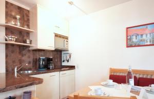 eine Küche mit weißen Schränken und einem Holztisch in der Unterkunft Inselresidenz Strandburg Juist - Wohnung 107 (Ref. 52044) in Juist
