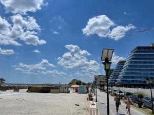 personnes marchant sur un trottoir près d'une plage avec un bâtiment dans l'établissement Ammi Residence - Mamaia Nord, à Mamaia Nord – Năvodari