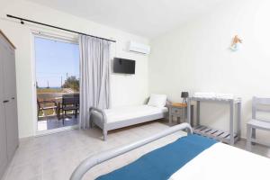 a bedroom with a bed and a balcony with a table at Pansion Artemis in Mavrovouni
