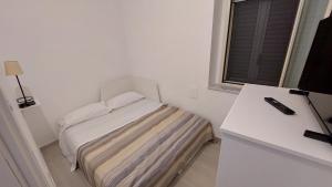 Habitación blanca pequeña con cama y ventana en Maison Don Turillo, en SantʼAlessio Siculo