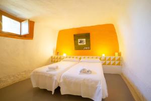 1 Schlafzimmer mit 2 Betten und weißer Bettwäsche in der Unterkunft Cuevas de las Bardenas in Valtierra