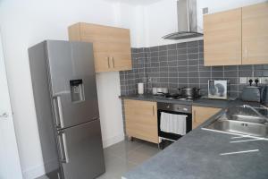 eine Küche mit einem Kühlschrank aus Edelstahl und einer Spüle in der Unterkunft Homely 1-Bed Apartment in Birmingham in Birmingham